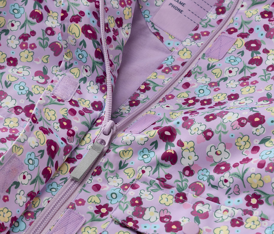Zbliżenie fioletowej kurtki dziecięcej w kwiaty, rozpiętej na zamek błyskawiczny.