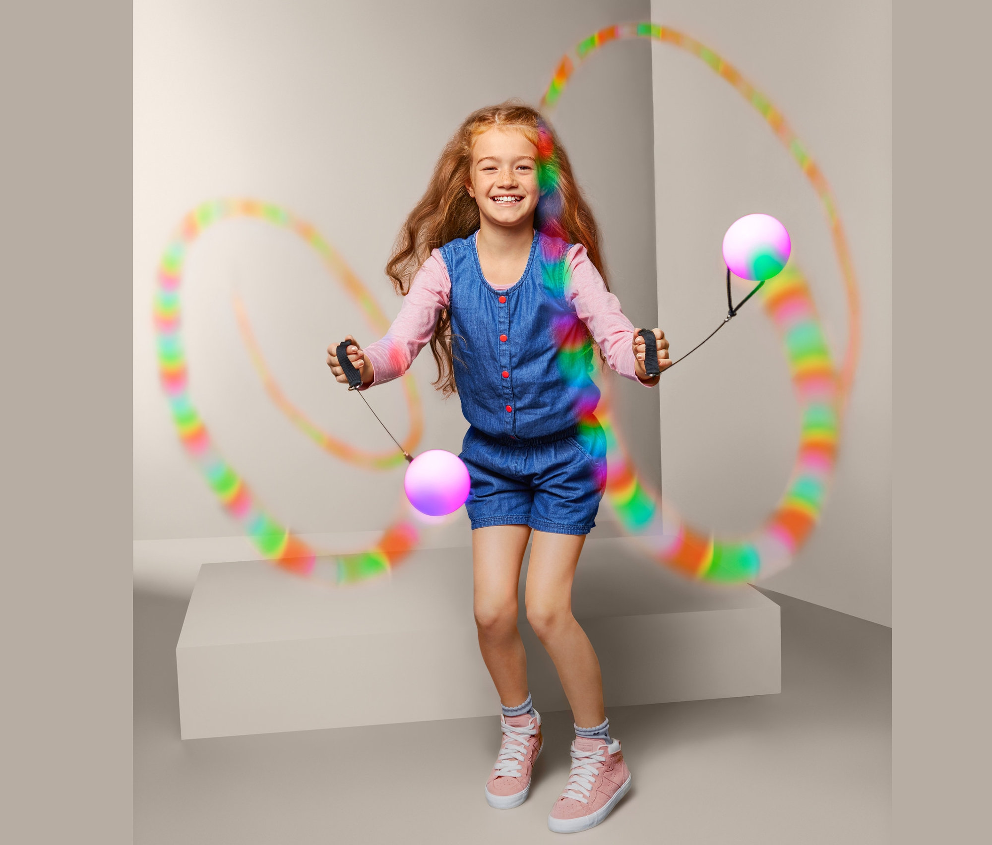 Uśmiechnięta dziewczyna żongluje parą kul LED na sznurku.