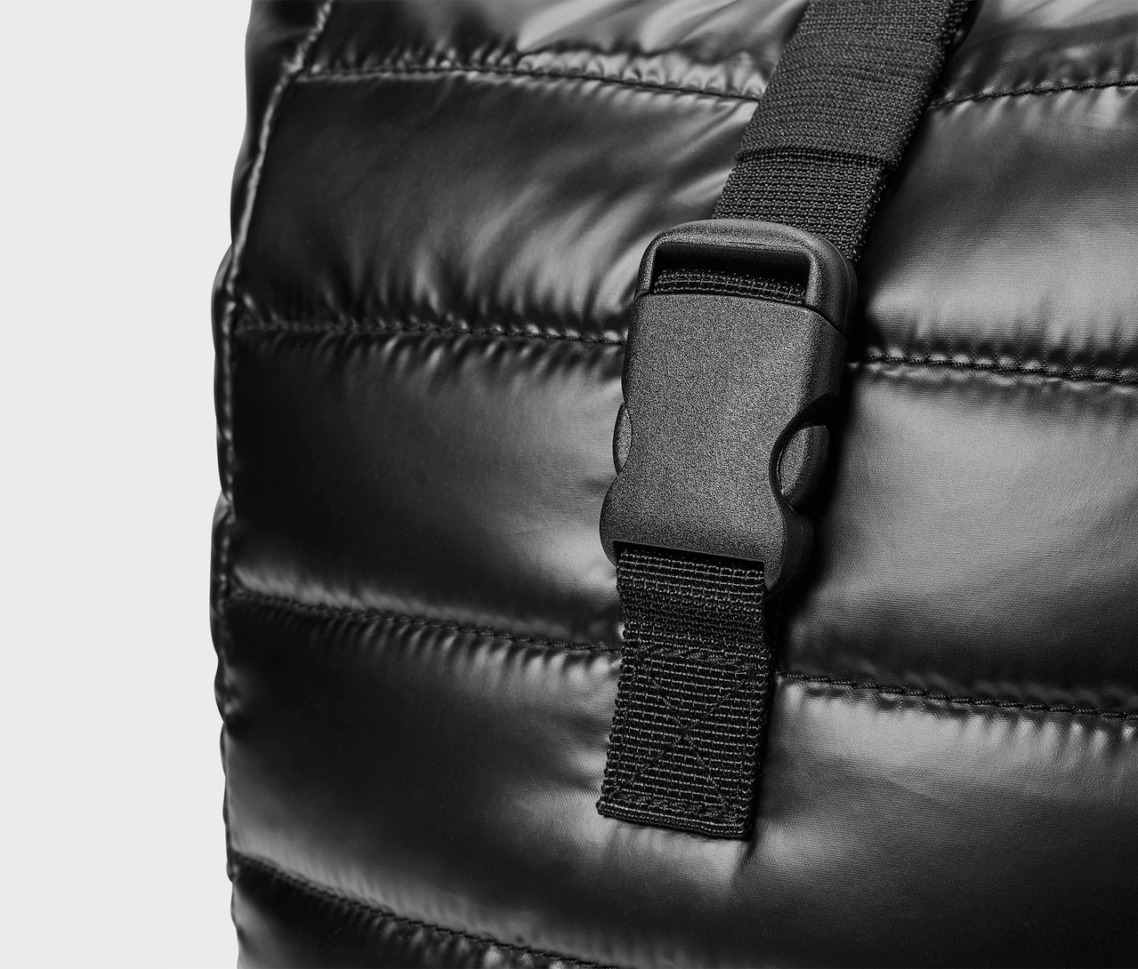 Szczegół czarnej, pikowanej torby z plastikową klamrą.