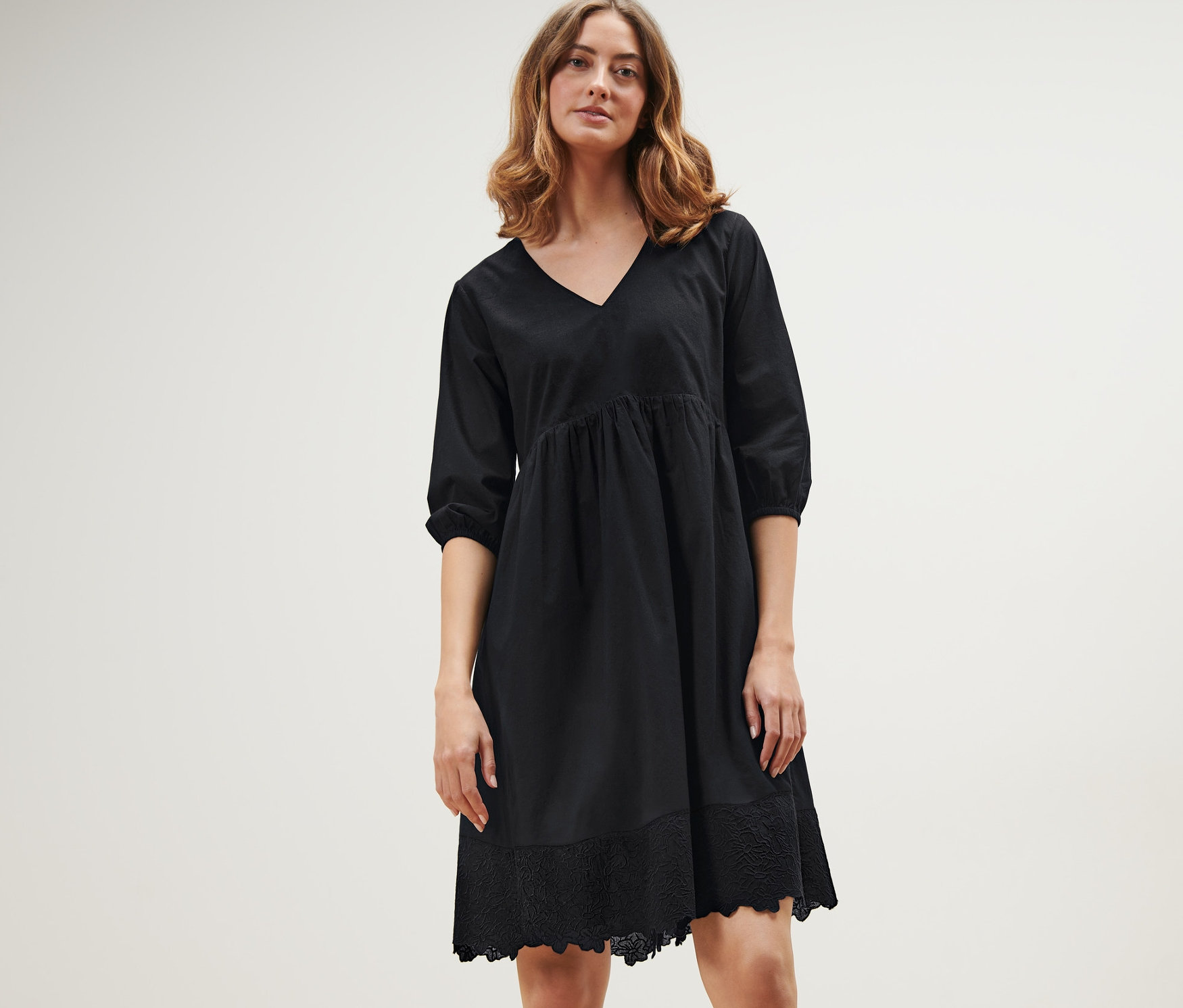 Kobieta pozuje w czarnej sukience z tkaniny z haftem.