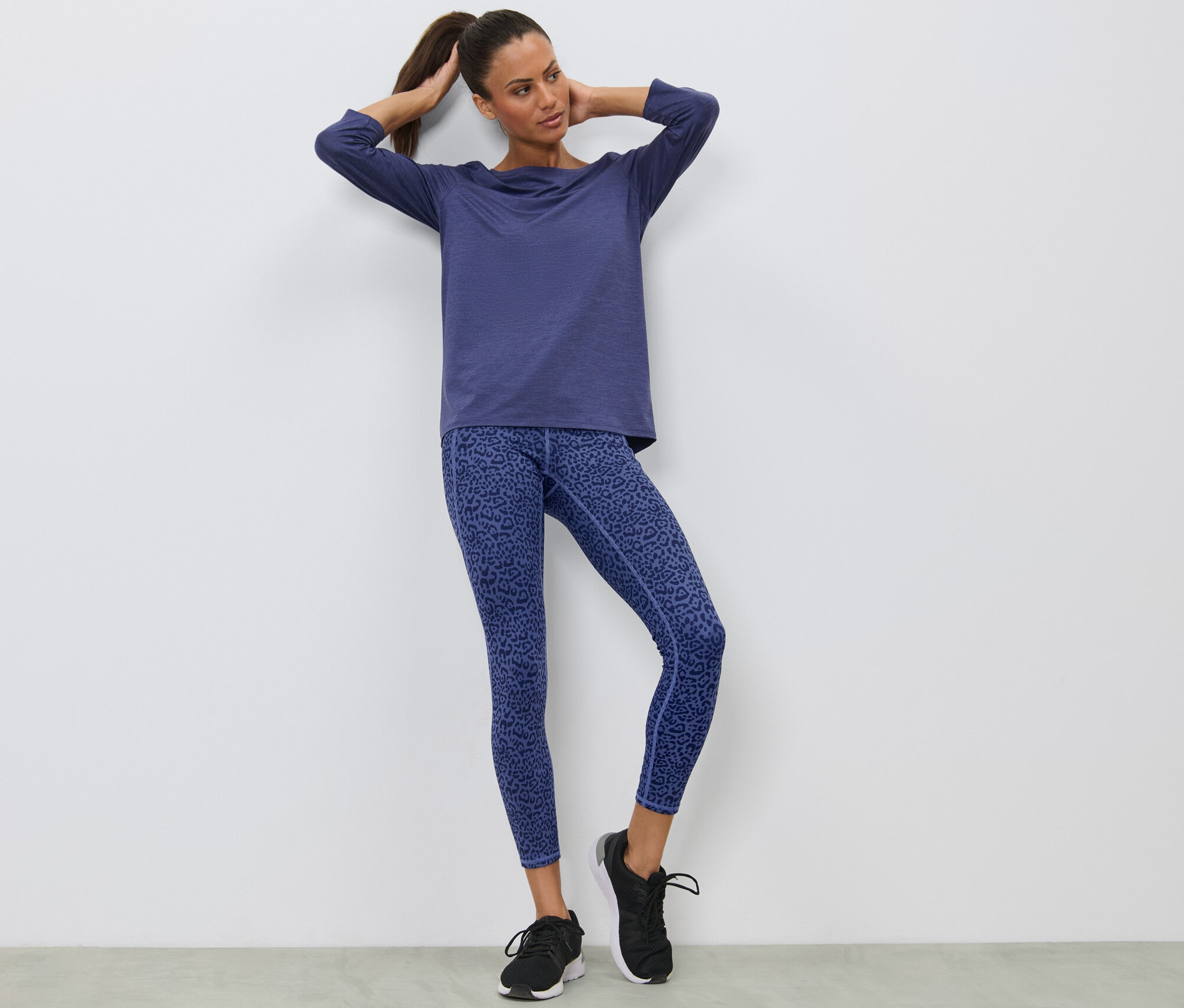 Kobieta pozuje w fioletowych legginsach sportowych.