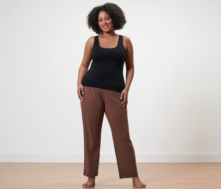 Kobieta stoi boso w spodniach od piżamy i czarnym podkoszulku.