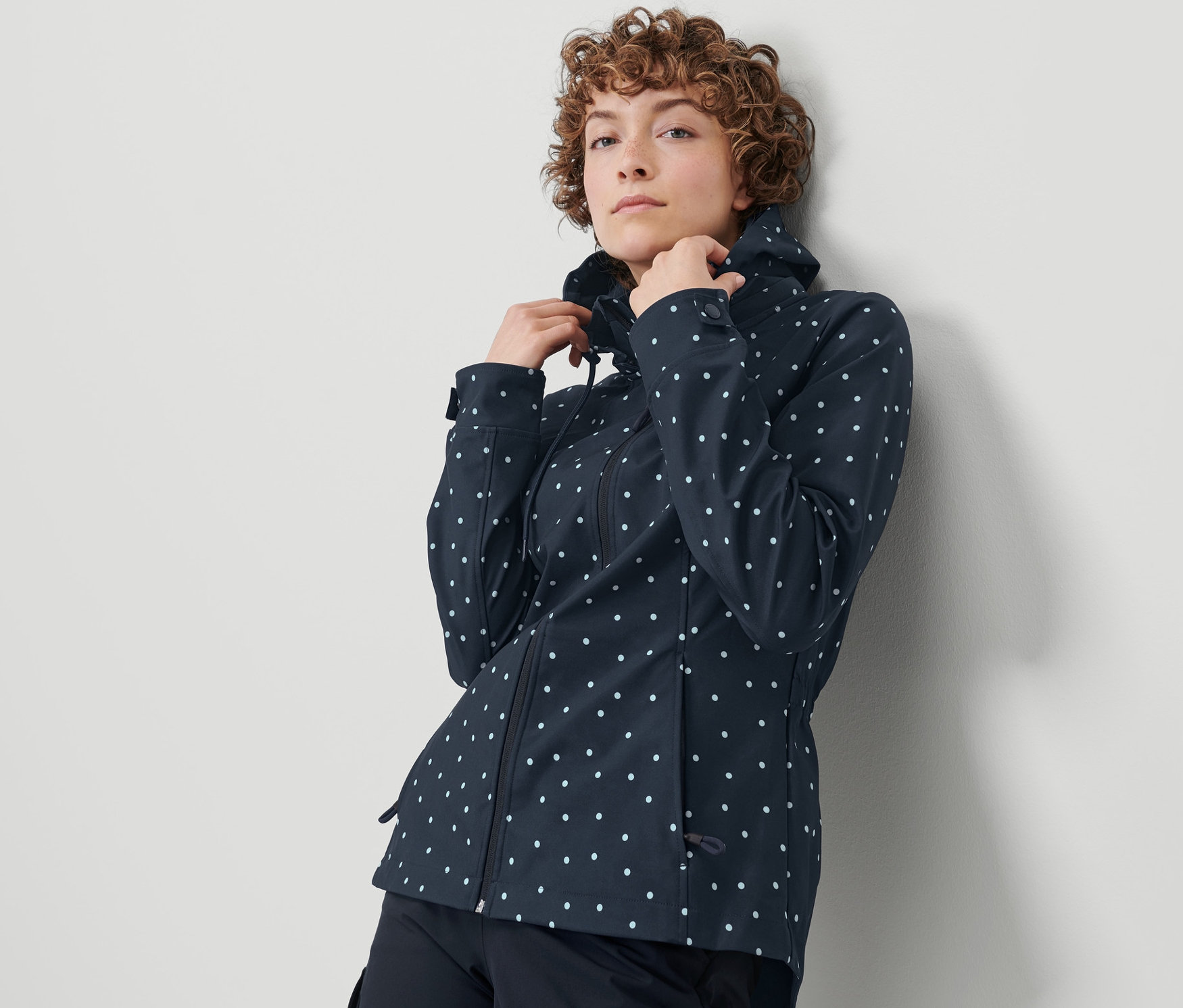 Kobieta poprawia kołnierz kurtki softshell w kropki.