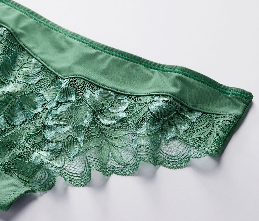 Zbliżenie na zielone figi brazylijskie, 4 pary, z kwiatową koronką na białym tle.