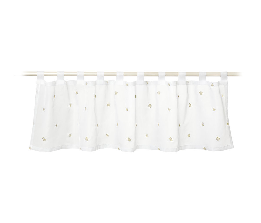 Biała zazdrostka ze złotymi gwiazdkami wisi na białym karniszu.