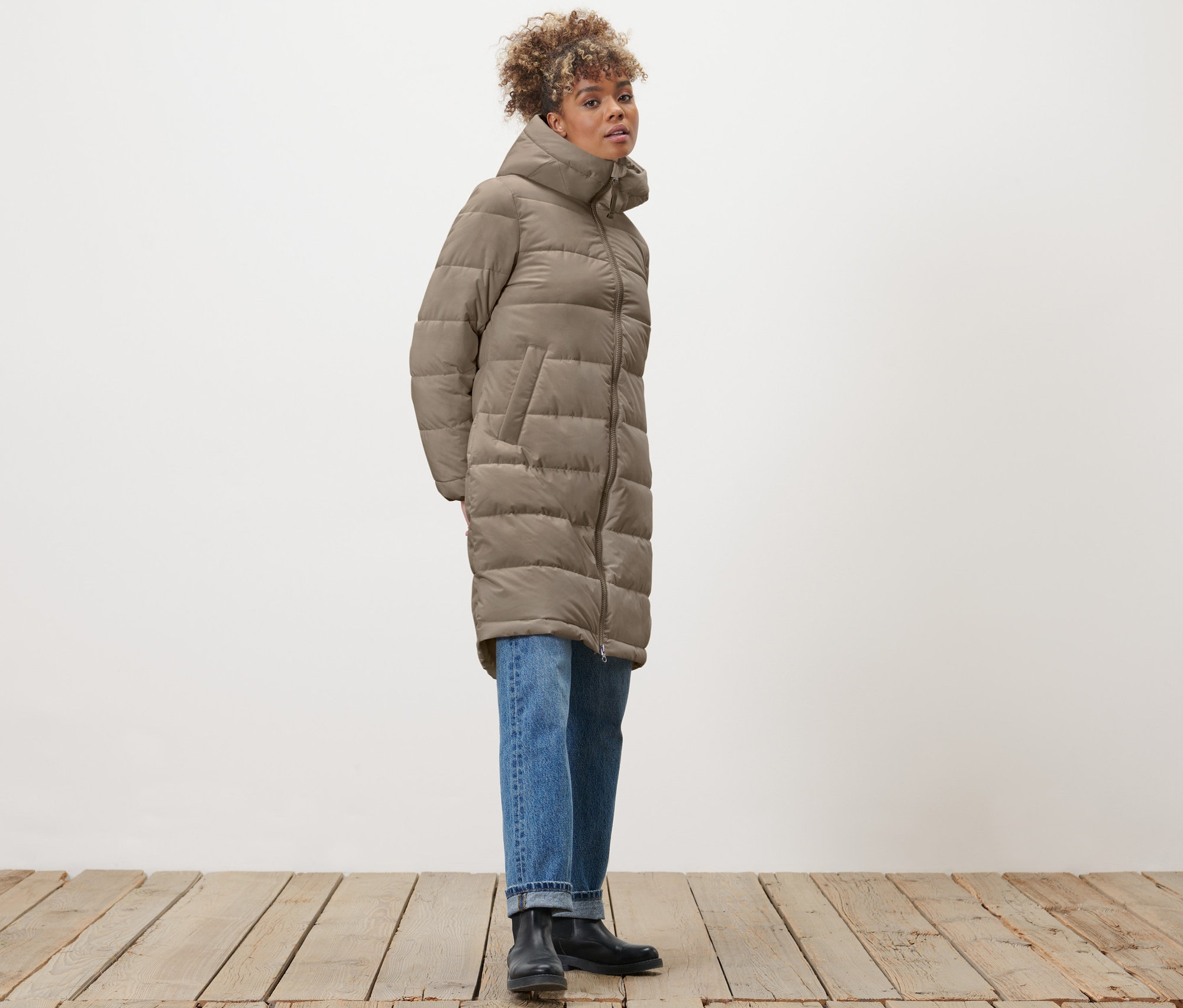 Kobieta pozuje w szarobeżowym pikowanym płaszczu.