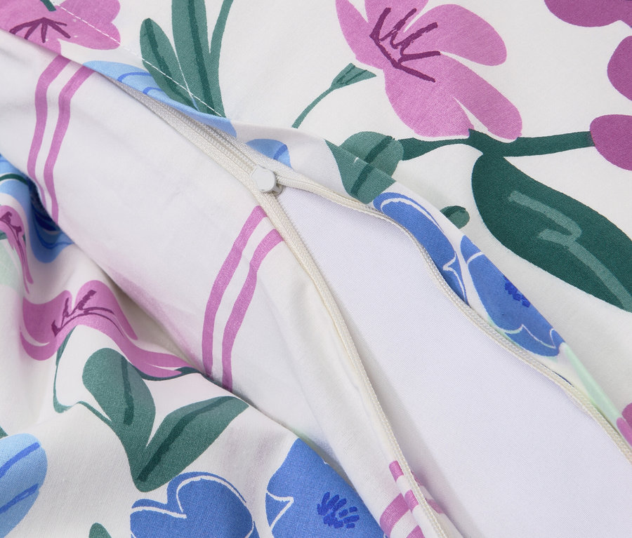 Zbliżenie na białą pościel z bawełny renforcé w kwiaty, zapinaną na zamek.