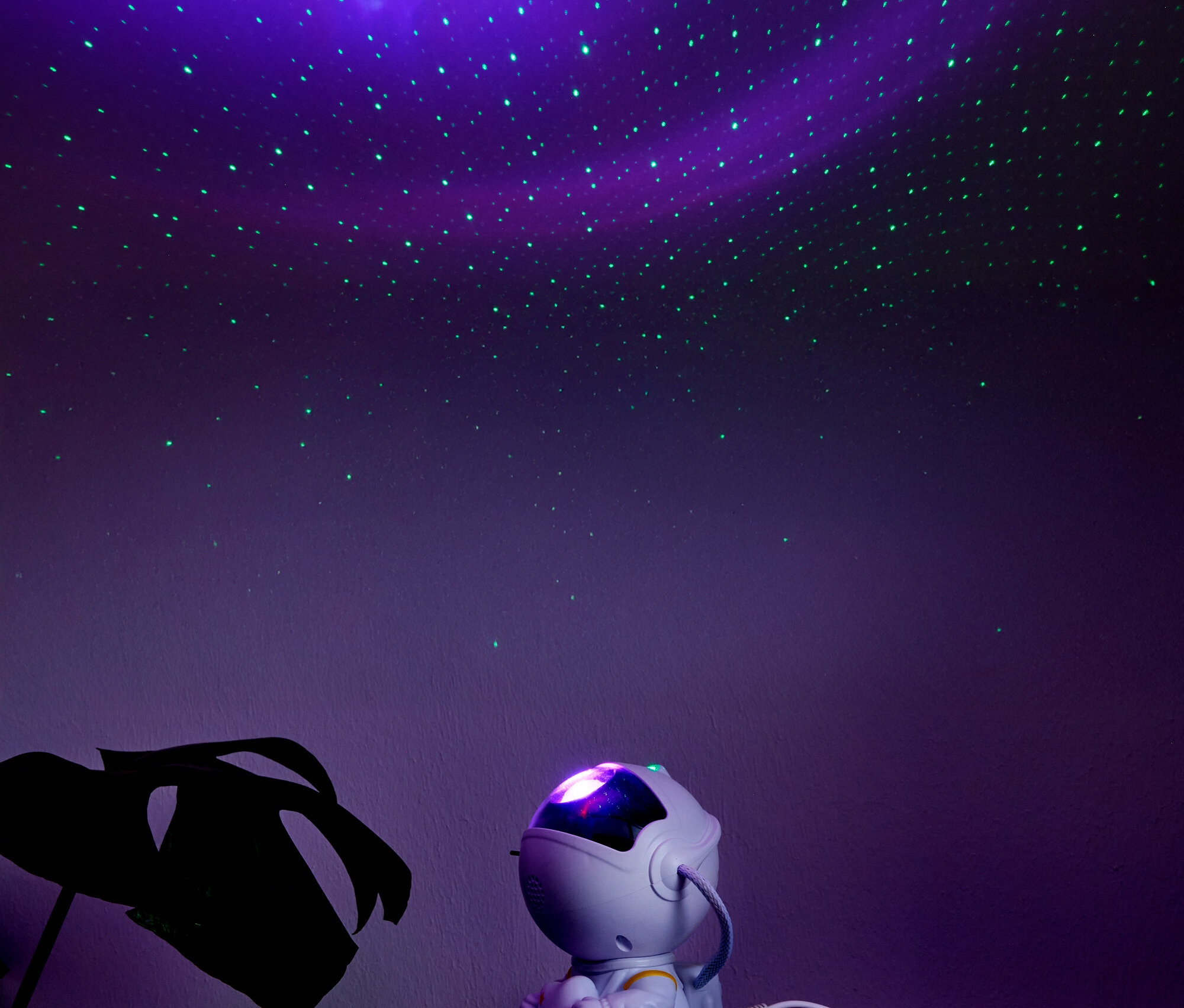 Astronauta siedzi na półce pod projekcją rozgwieżdżonego nieba.
