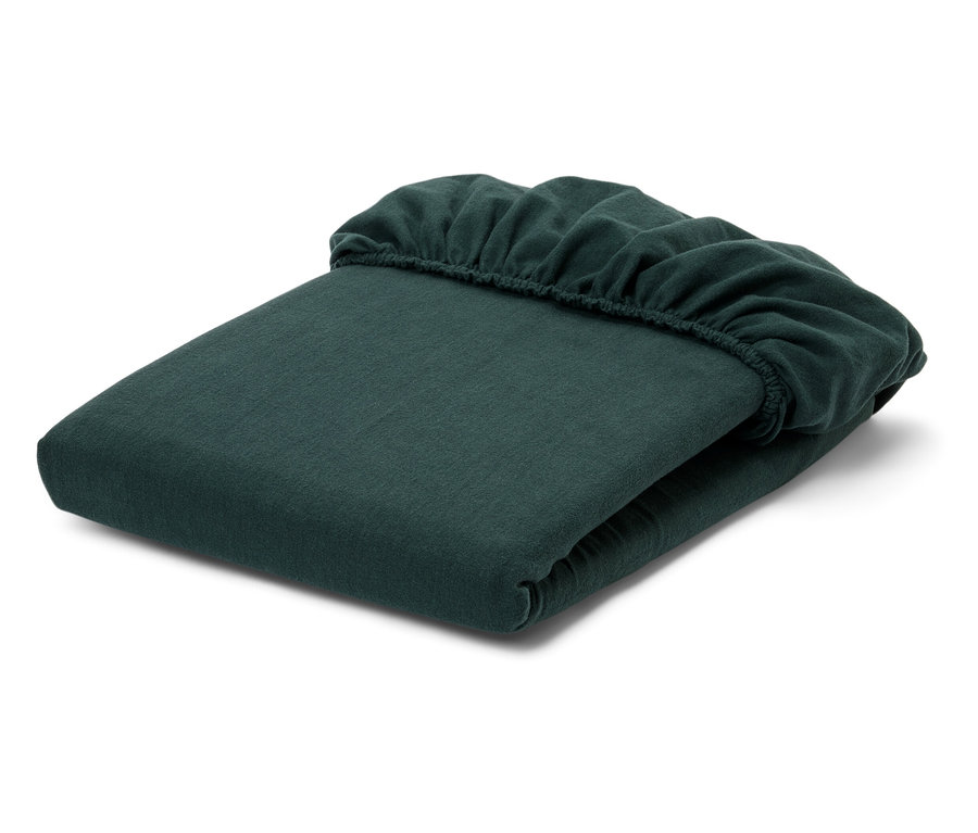 Złożone zielone prześcieradło z gumką na białym tle.