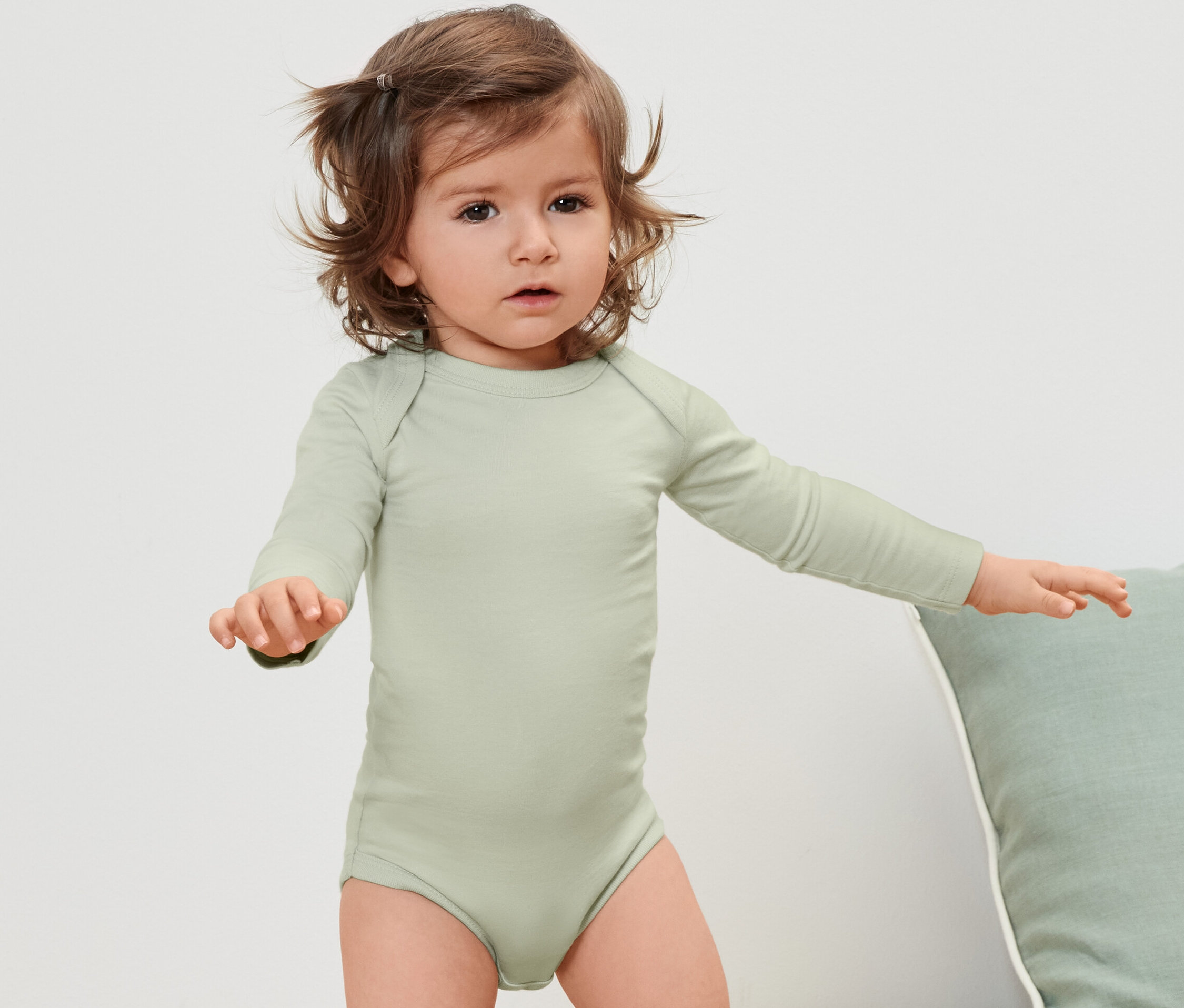 Niemowlę w zielonym body z długim rękawem.