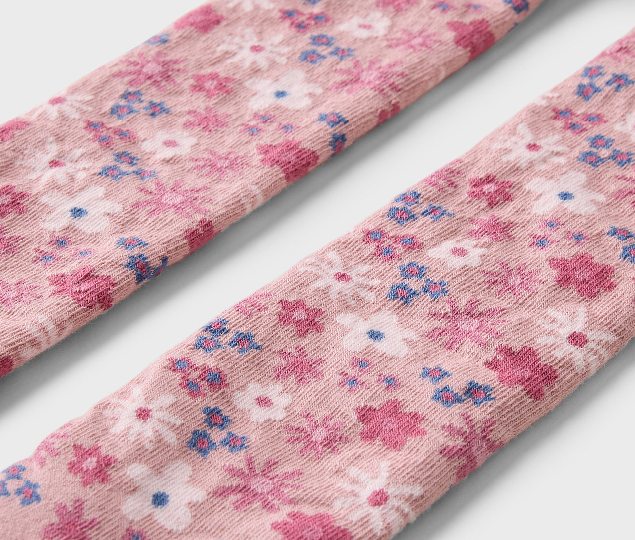 Szczegół trzech par dziecięcych rajstop we wzór w kwiaty.