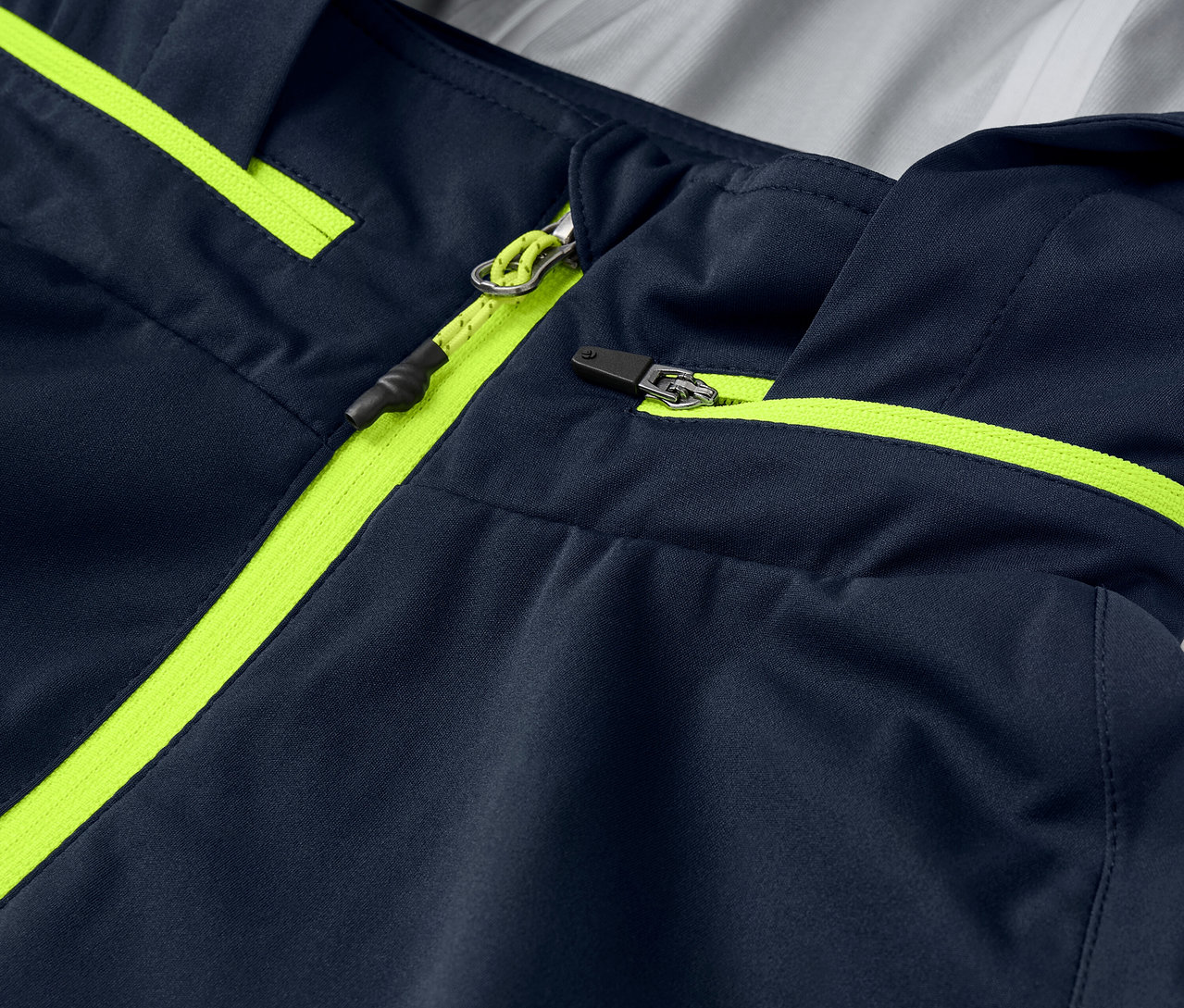 Szczegółowy widok kurtki przeciwdeszczowej rowerowej z neonowożółtymi detalami zamka błyskawicznego i lamówką.