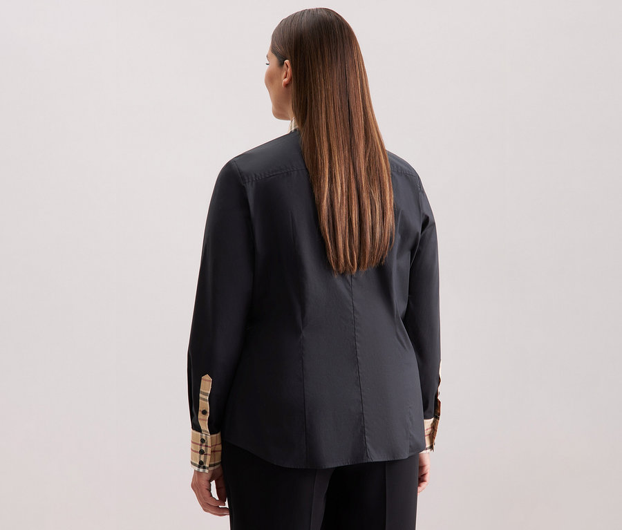 Widok z tyłu na kobietę z długimi brązowymi włosami ubraną w czarną popelinową bluzkę Seidensticker z detalami w kratę.