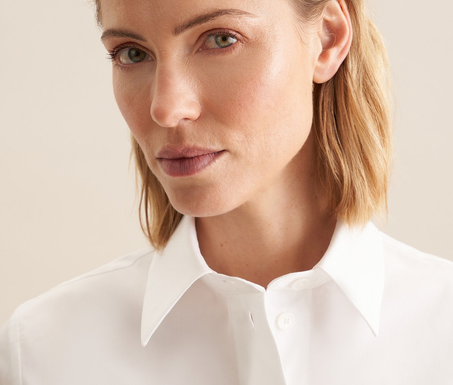 Portret blondwłosej kobiety w białej koszuli z krótkim rękawem Seidensticker.