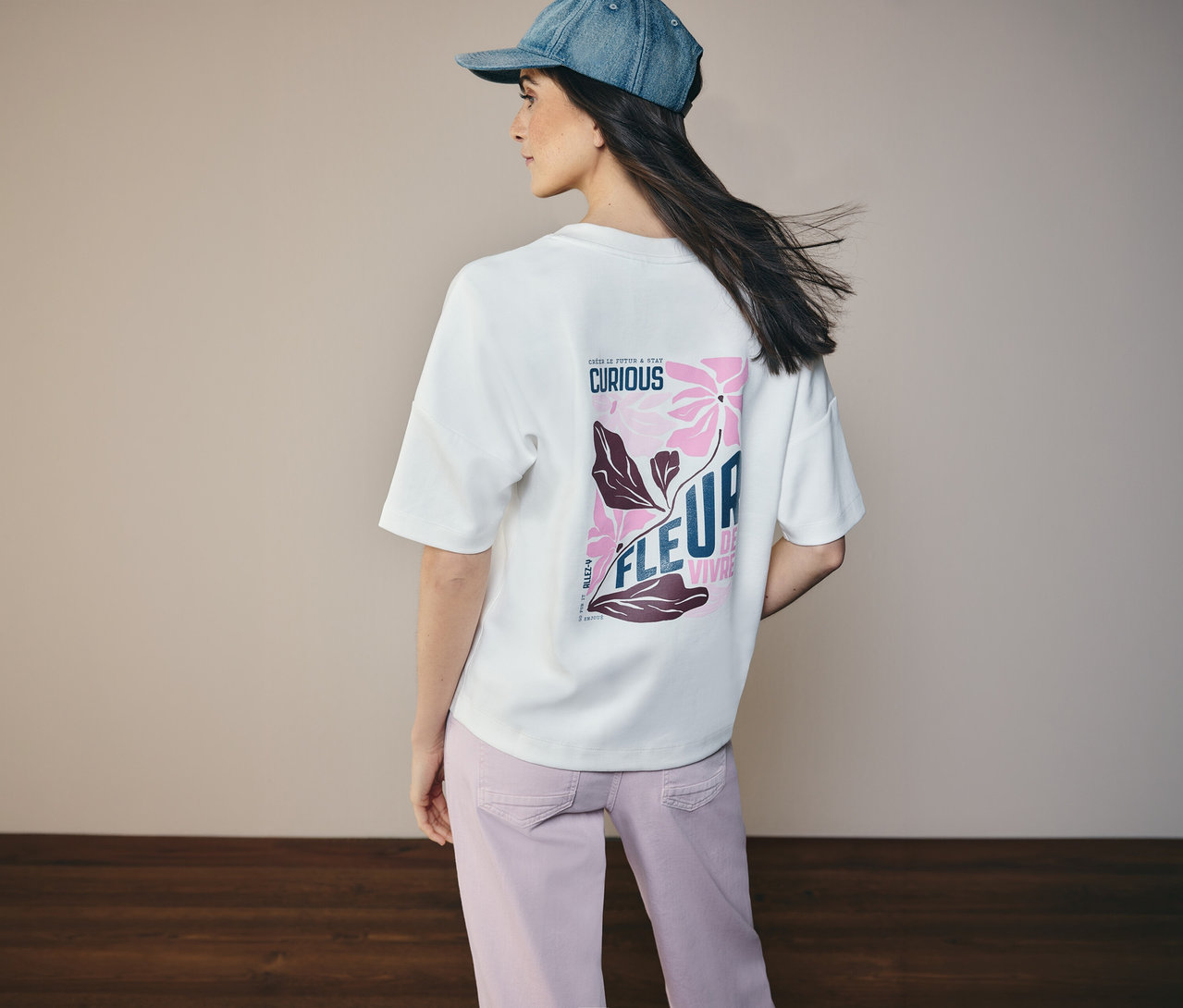 Kobieta z tyłu w dżinsowej kurtce i koszulce CECIL z kwiatowym wzorem na plecach.