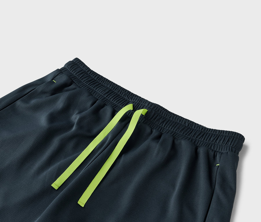 Zbliżenie na ciemnoszare spodenki ze sznurkiem w kolorze jasnozielonym.