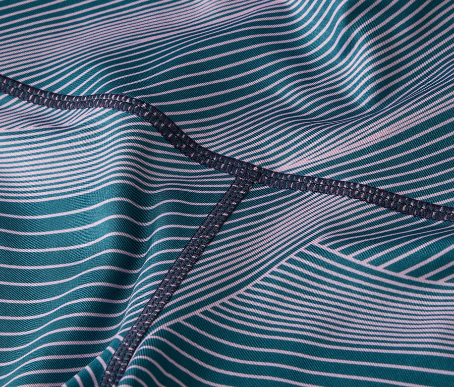 Zbliżenie materiału legginsów w turkusowo-białe paski z ciemnymi szwami.