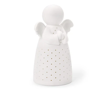 Biała ceramiczna figurka anioła z kulistą głową, małymi skrzydłami i złożonymi dłońmi. Jej stożkowaty korpus pokryty jest małymi, okrągłymi otworami.