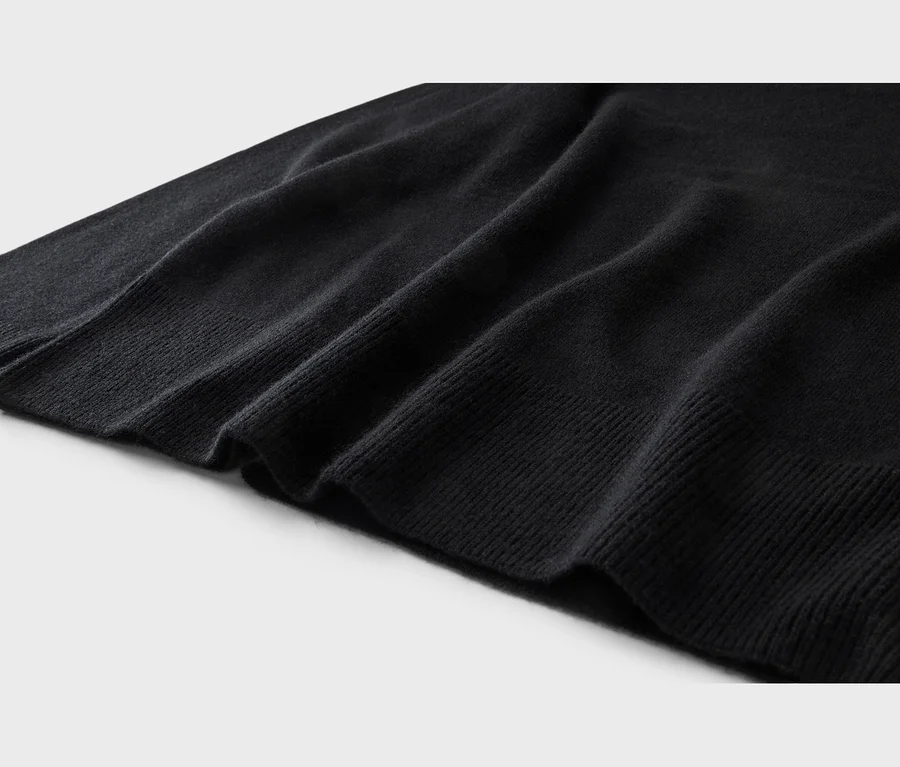 Zbliżenie czarnej dzianiny, ukazujące miękkie fałdy i prążkowany brzeg na jasnym tle.