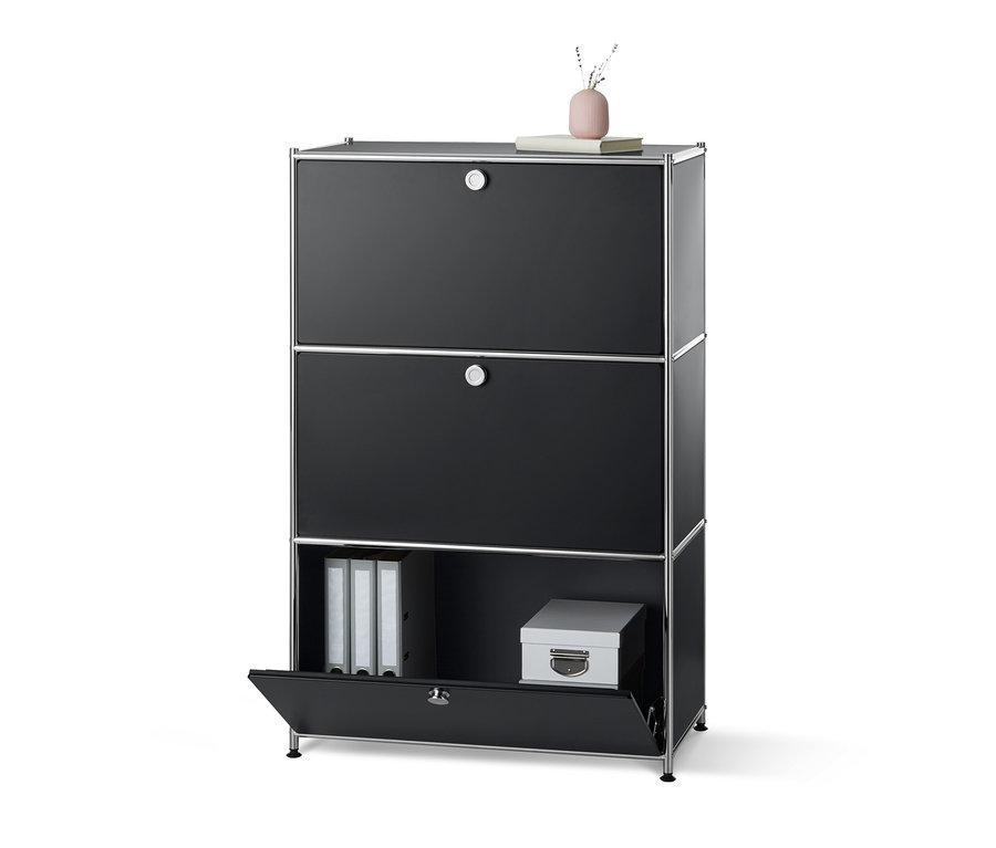 Czarna, metalowa szafka z 3 przegrodami z klapą, z których dolna jest otwarta.