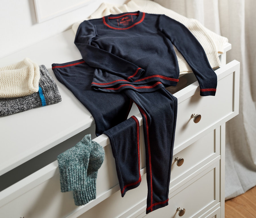 Dziecięca bielizna funkcyjna leży na otwartej szufladzie komody.