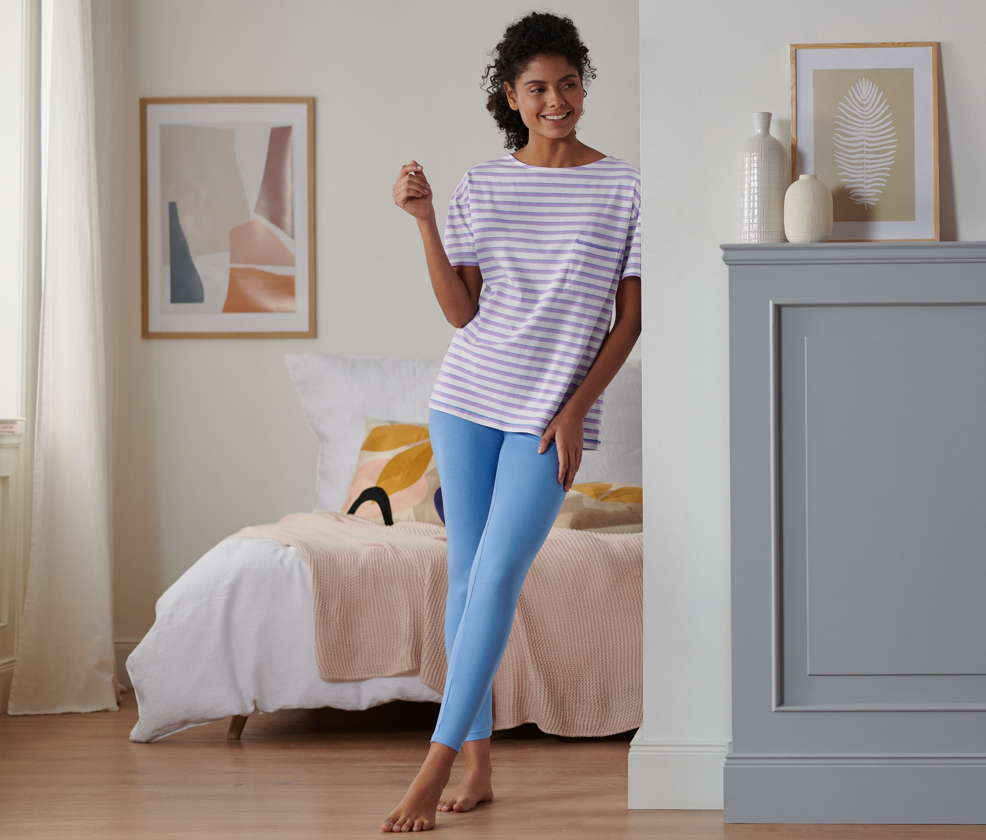 Kobieta stoi w sypialni w piżamie z legginsami.