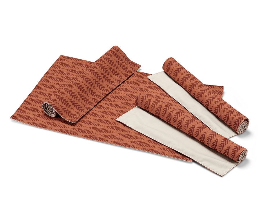 Rozłożone i zwinięte dwustronne podkładki pod talerze, 4 sztuki, z terakotowym wzorem liści na beżowym tle.