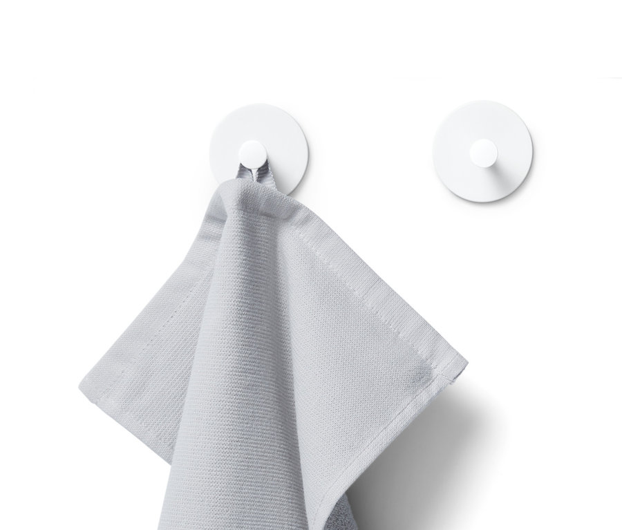 Szary ręcznik wisi na białym haczyku, w tle widoczny jest kolejny biały haczyk.