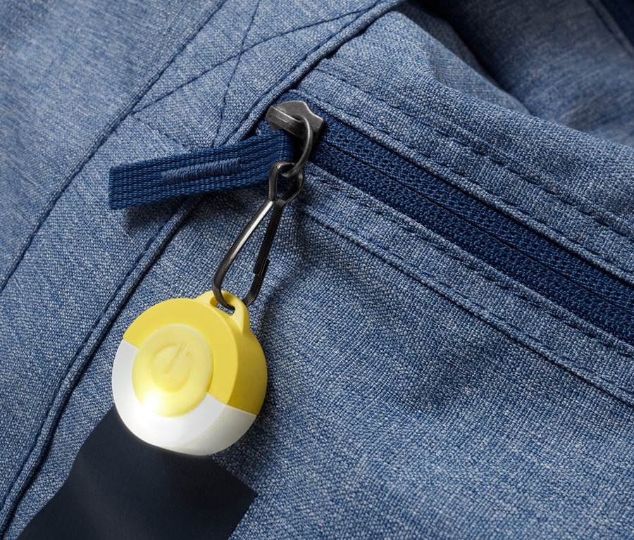 Zbliżenie na niebieską kurtkę z materiału z zamkiem błyskawicznym i żółto-białą przywieszką LED.