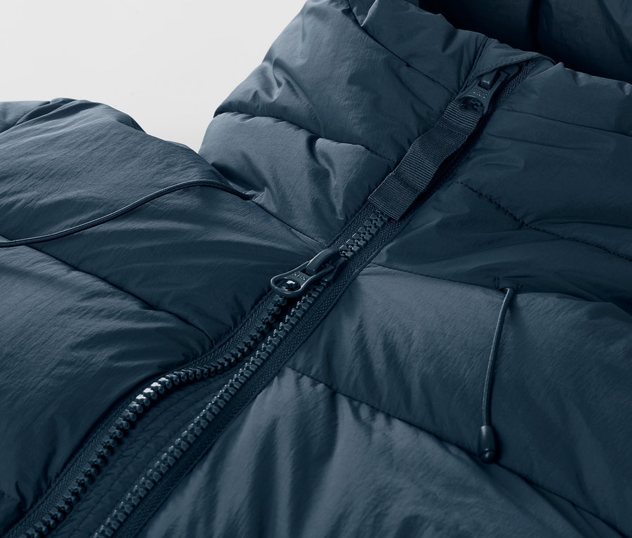 Zbliżenie na granatową, pikowaną kurtkę narciarską z zamkiem błyskawicznym.