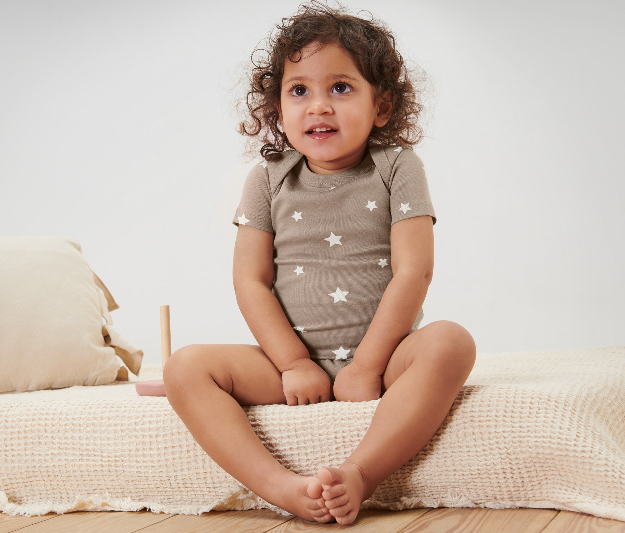 Dziecko siedzi na łóżku i ma na sobie body z krótkim rękawem, 5 sztuk.