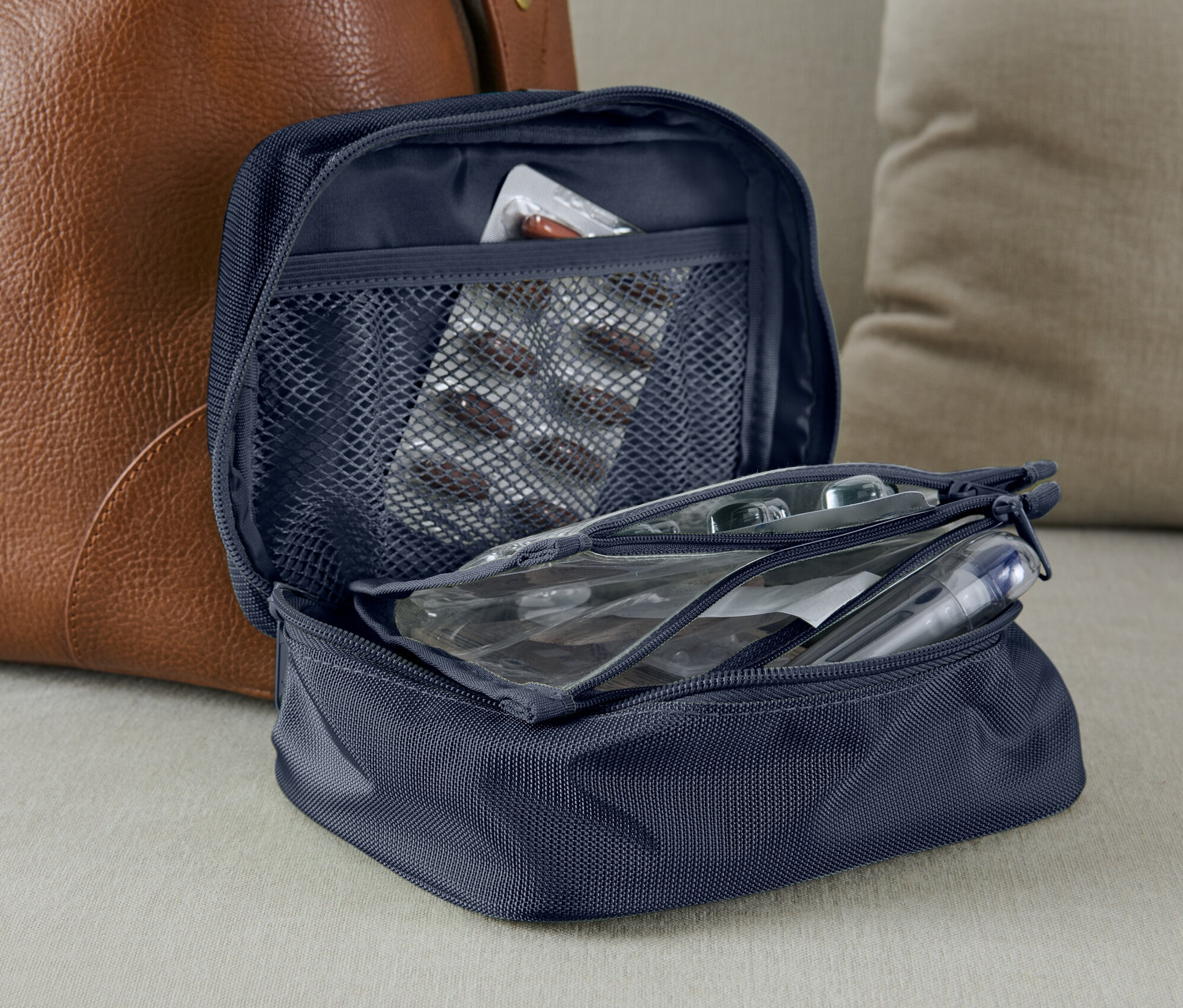 Otwarta niebieska kosmetyczka na leki z blistrem leków w siatkowej kieszeni.