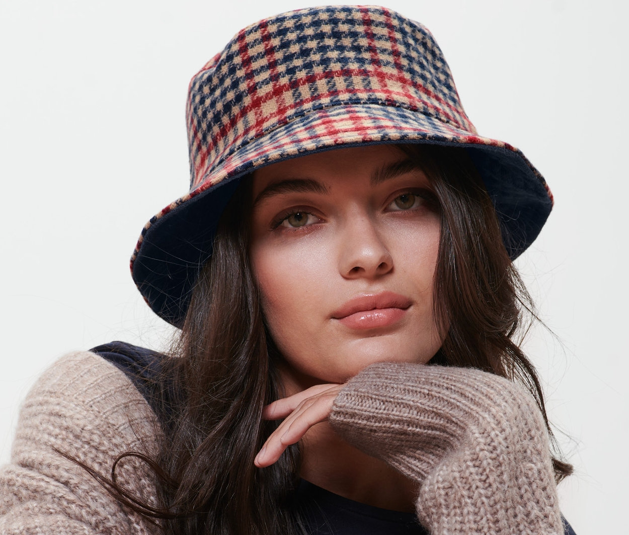 Kobieta siedzi na krześle i ma na sobie dwustronny kapelusz typu bucket hat.