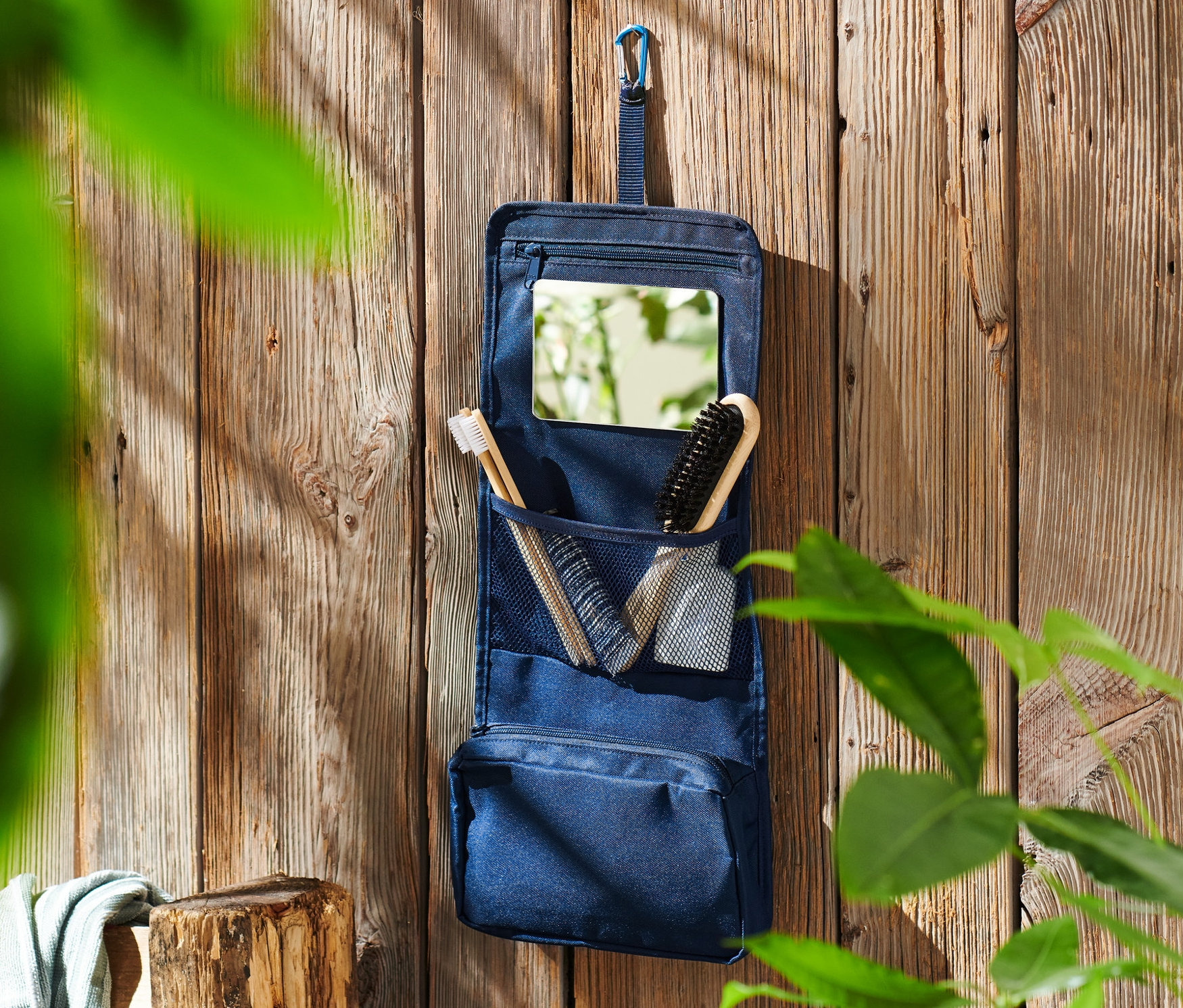 Niebieska kosmetyczka wisi na drewnianej ścianie.