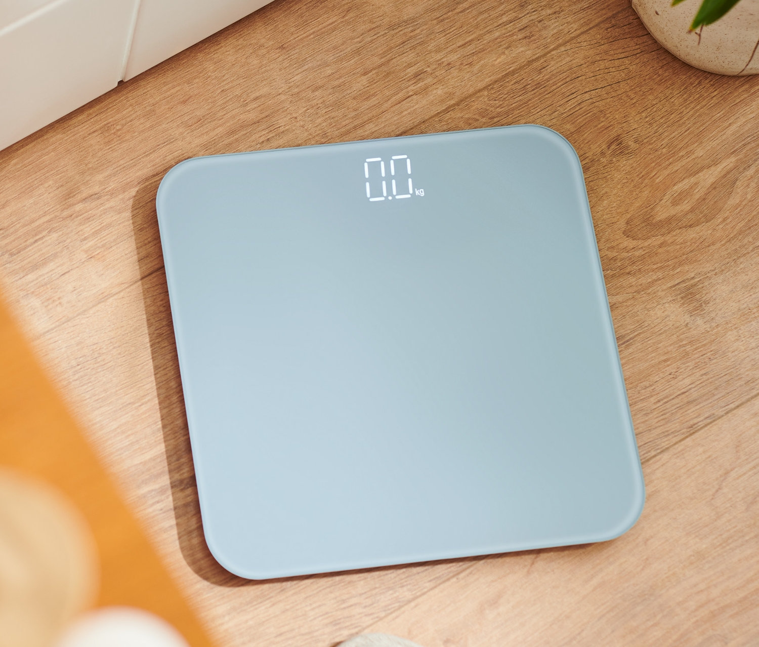 Cyfrowa waga łazienkowa na drewnianej podłodze.
