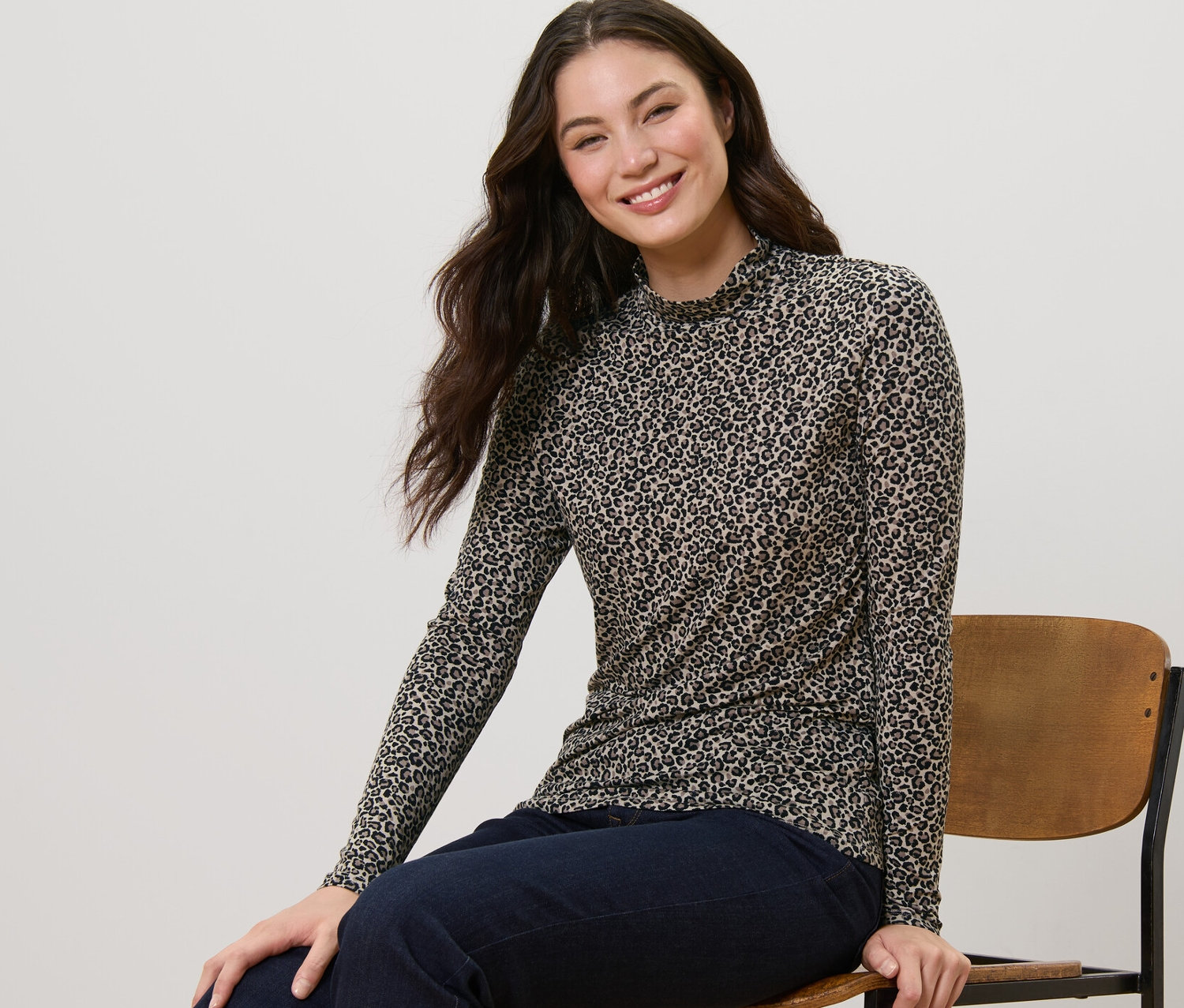 Kobieta siedzi na krześle i ma na sobie wzorzystą bluzkę ze stójką.