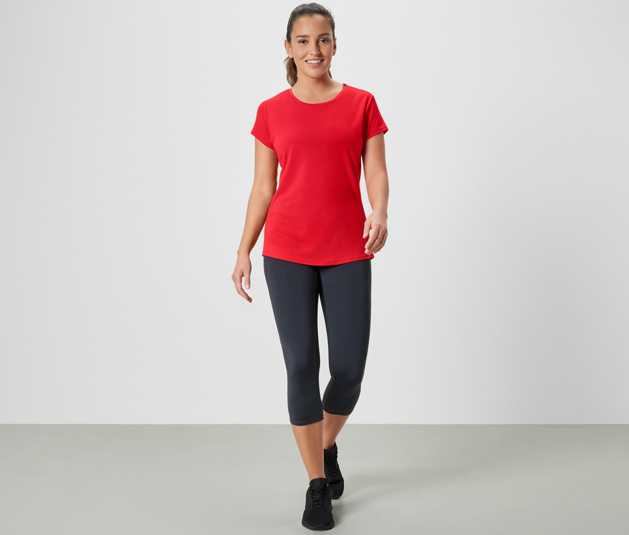 Kobieta idzie i ma na sobie czerwoną koszulkę sportową.