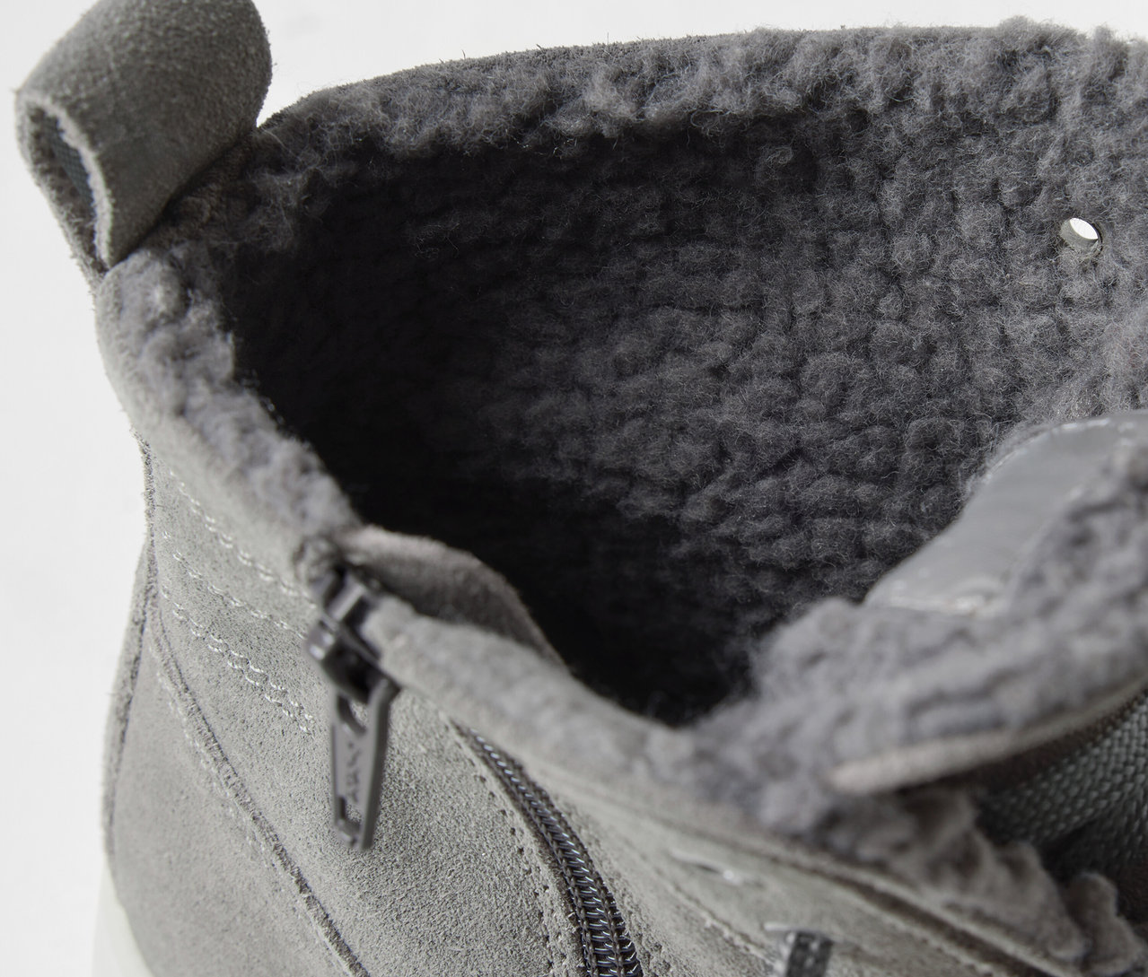 Szczegół szarego sznurowanego buta do kostki z wewnętrznym futrem i zamkiem błyskawicznym.