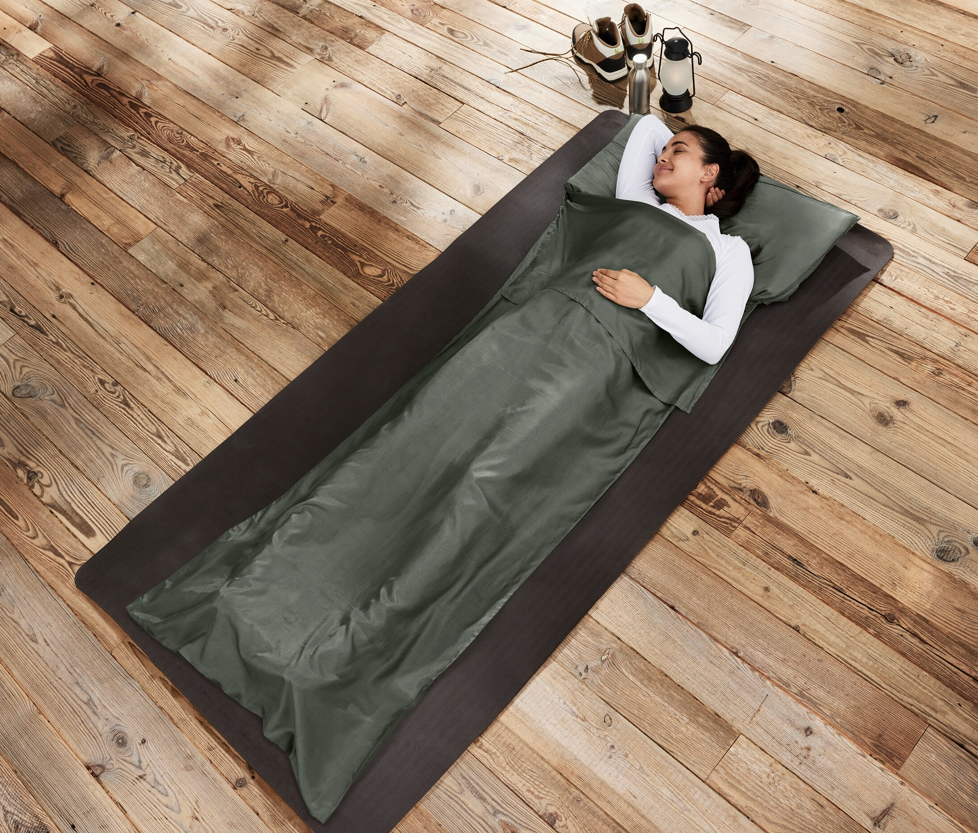 Kobieta leży na macie w jedwabnej wkładce do śpiwora.