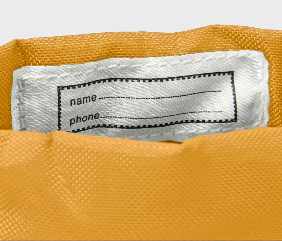 Zbliżenie na żółte kalosze dziecięce z białą plakietką na imię.