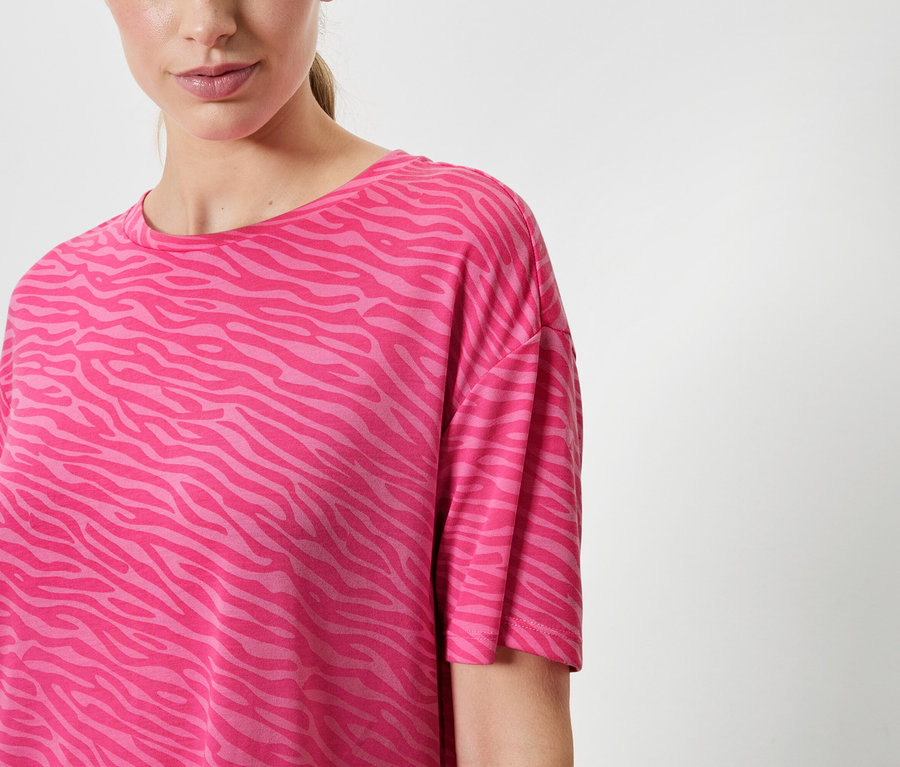 Kobieta ma na sobie różowy T-shirt w zwierzęcy wzór.