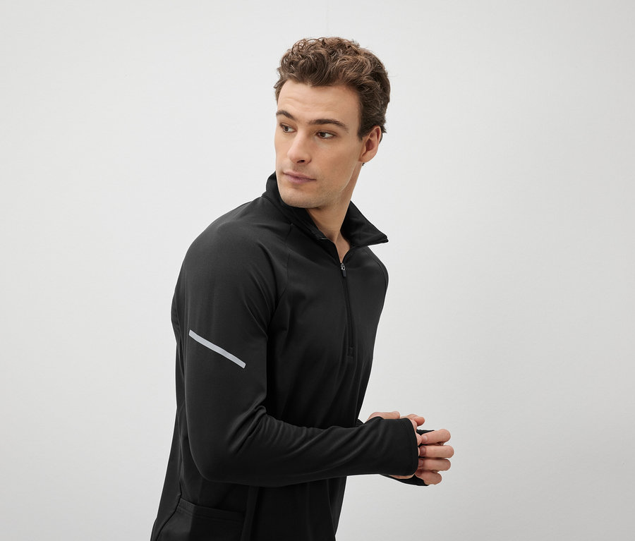 Mężczyzna w czarnym topie sportowym spogląda przez ramię.