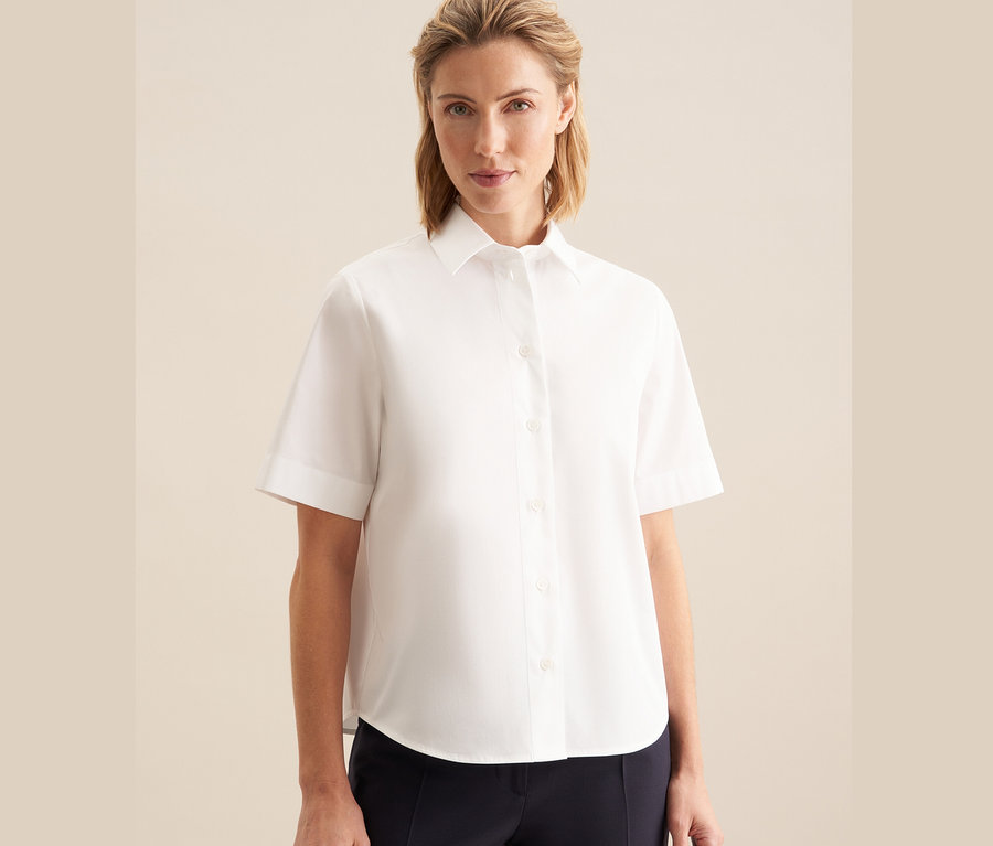 Kobieta ma na sobie białą koszulę z krótkim rękawem Seidensticker.