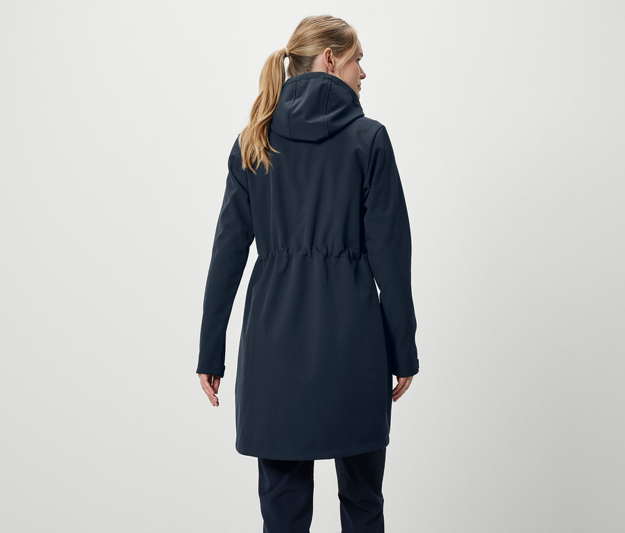 Widok z tyłu kobiety z blond włosami związanymi w kucyk, ubranej w granatowy płaszcz i spodnie.