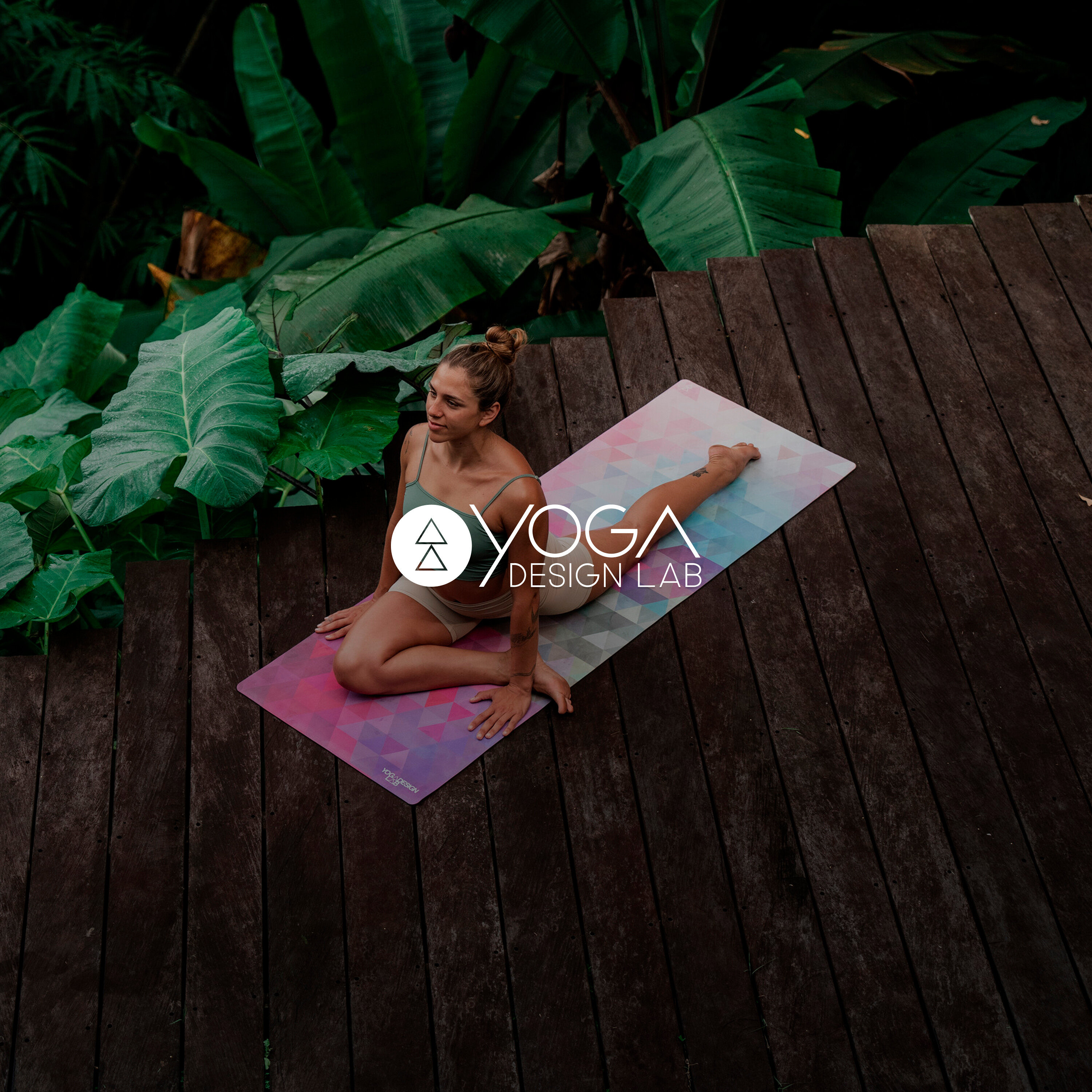 Kobieta siedzi na macie do jogi na drewnianej podłodze.