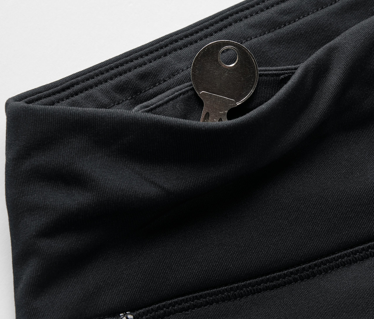 Szczegół czarnych legginsów z kluczem w kieszeni.