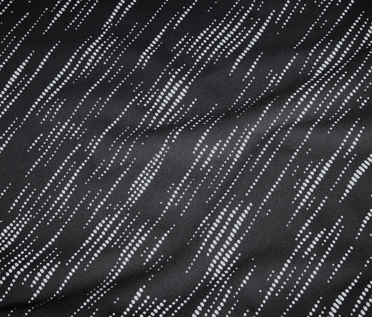 Zbliżenie na czarną tkaninę z ukośnymi, kropkowanymi, białymi liniami.
