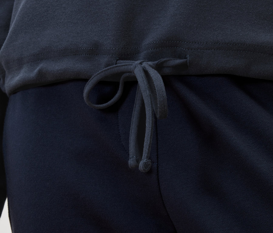 Szczegółowy widok granatowej bluzy ze sznurkiem nad granatowymi spodniami.