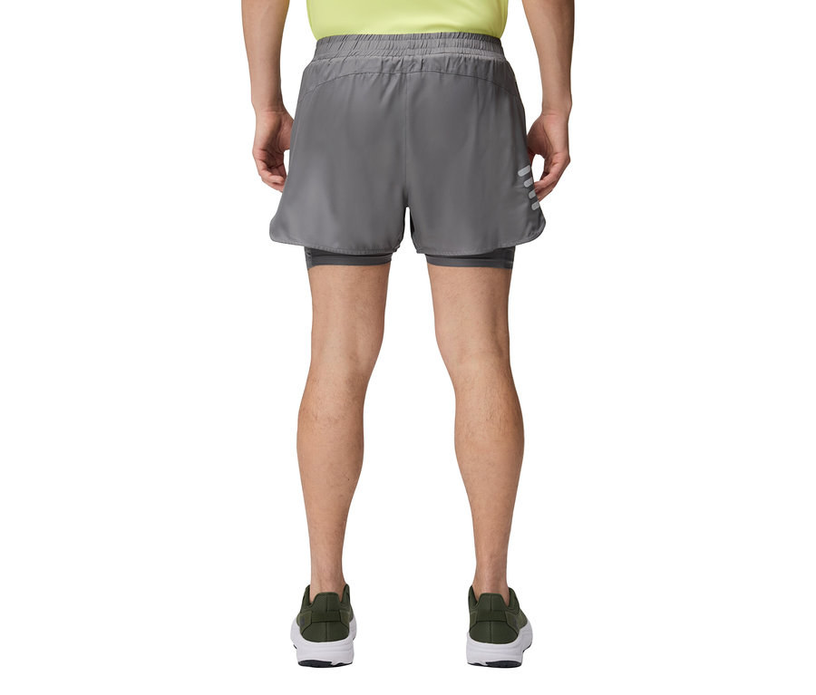 Mężczyzna widziany od tyłu, ubrany w szare spodenki i zielone buty.