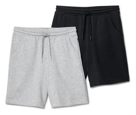 Dwie pary krótkich spodenek dresowych, jedna szara i jedna czarna, leżą obok siebie.